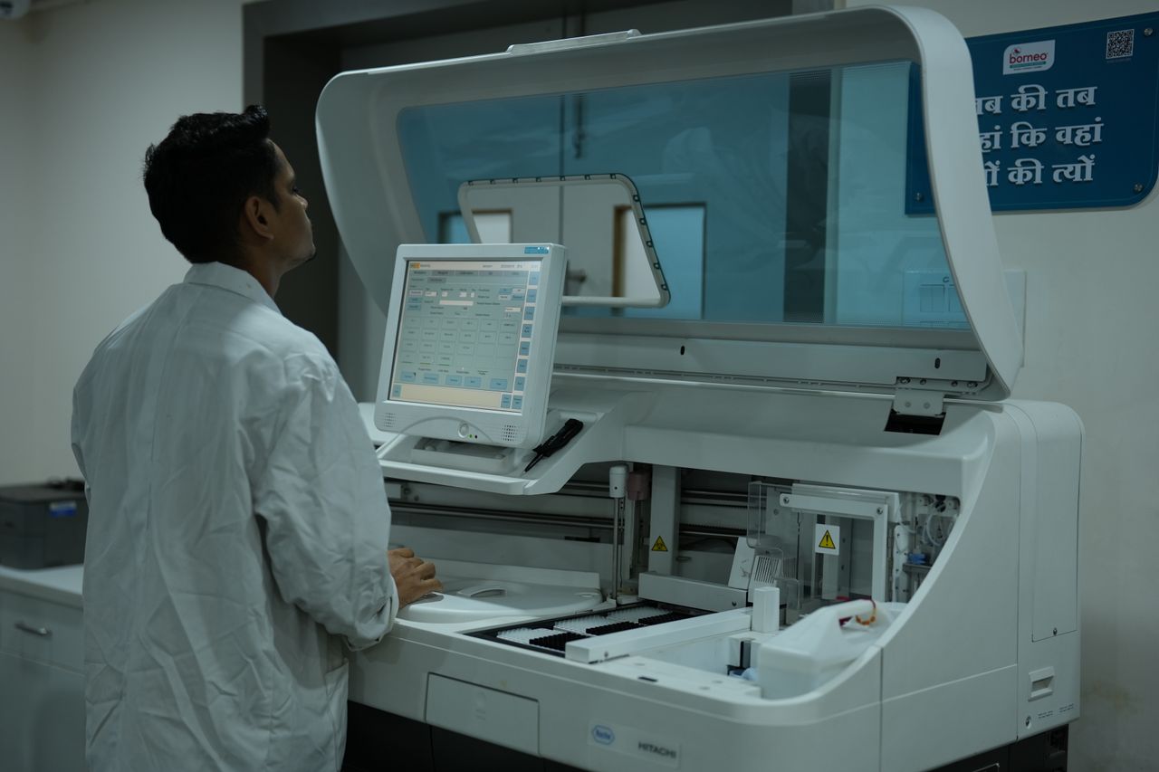 embark A lab technician operates a clinical analyzer in a modern laboratory setting.